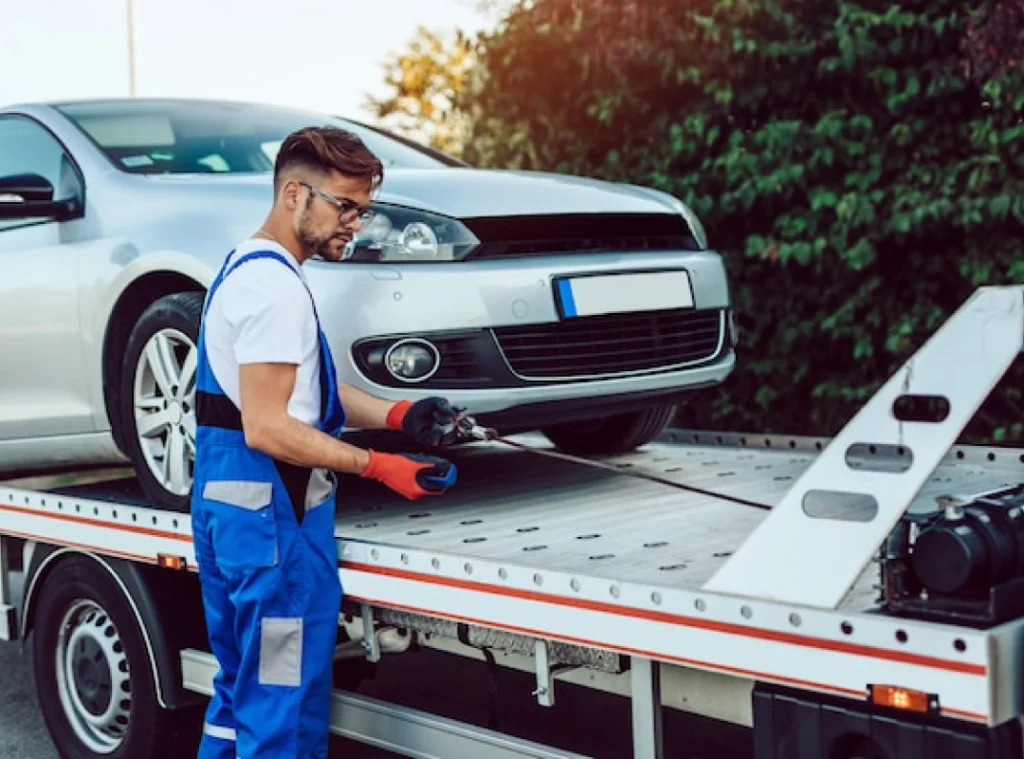 a person in overalls loading a car on a flatbed truck