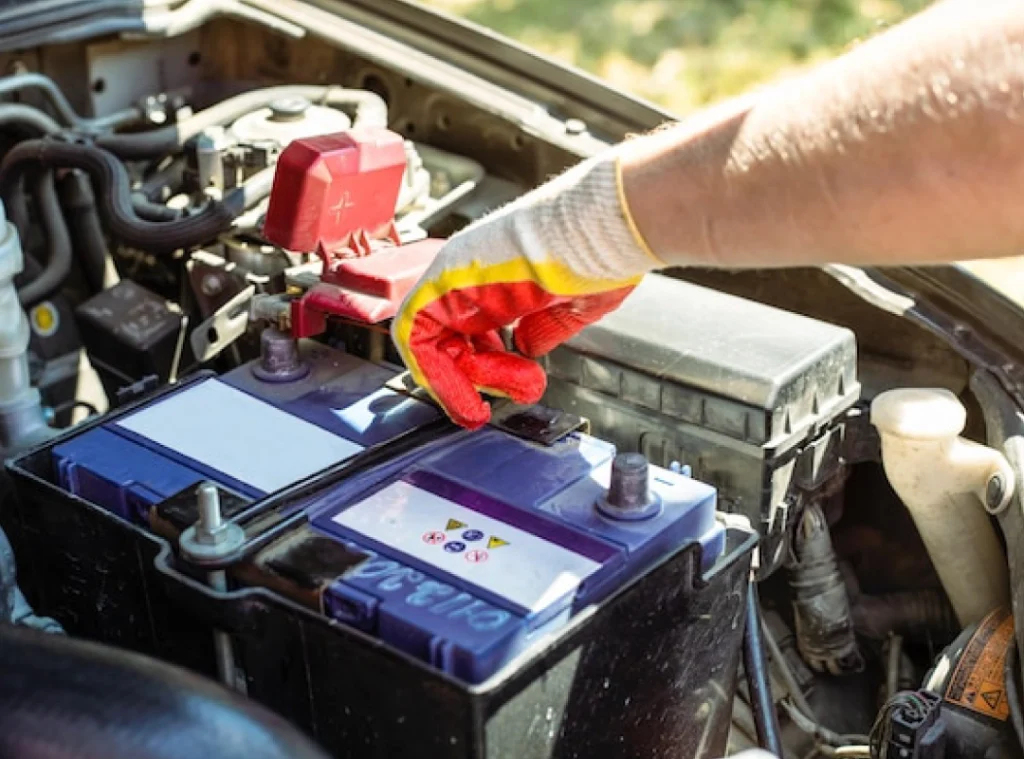 a hand in glove holding a battery