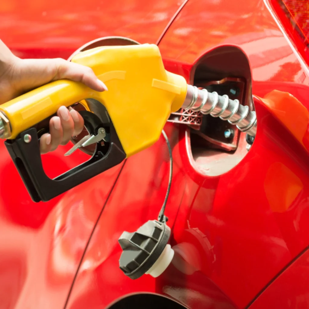 a hand holding a yellow gas gun to refill a red car