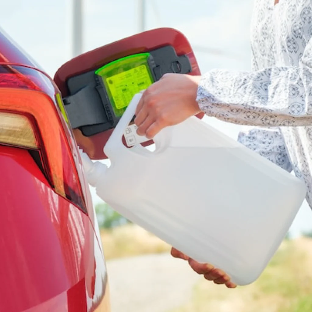 a person filling up a car with a gallon of gasoline