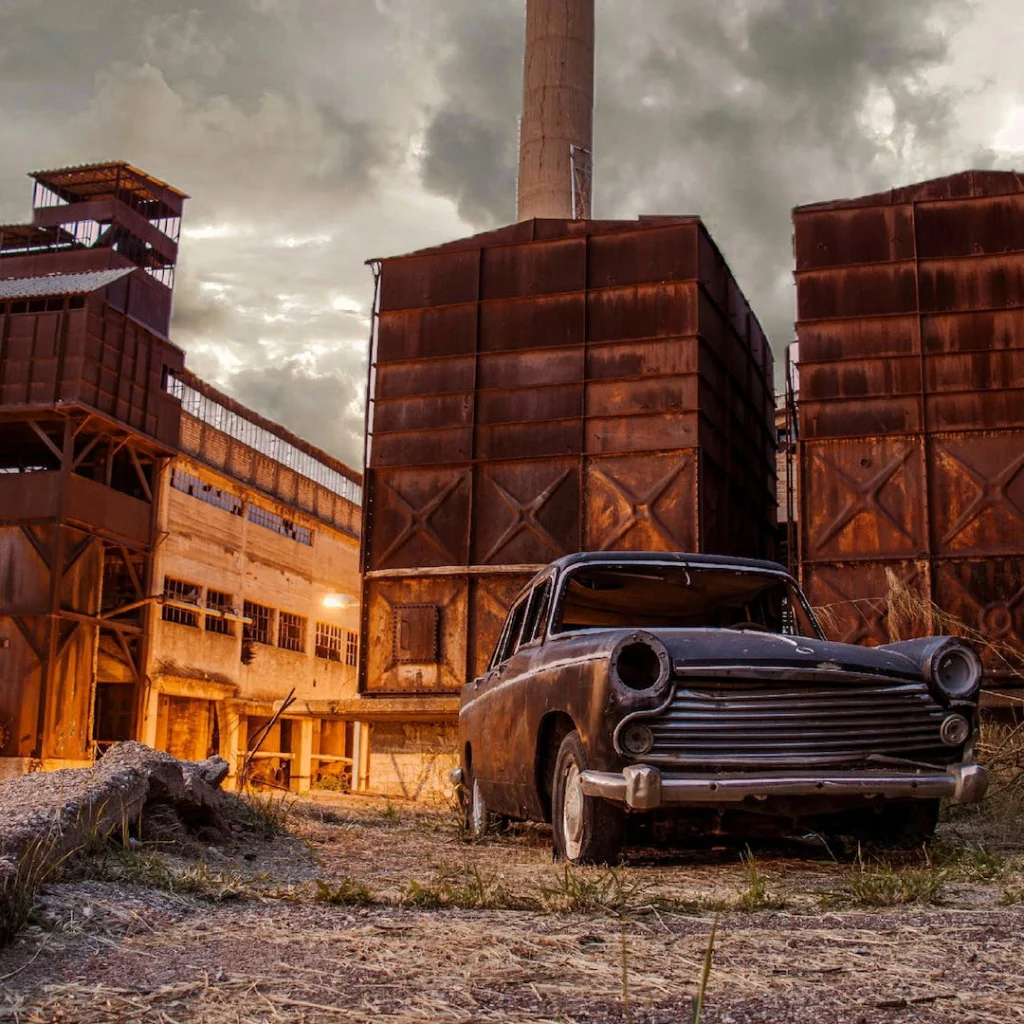 an old car in front of rusty metal structures